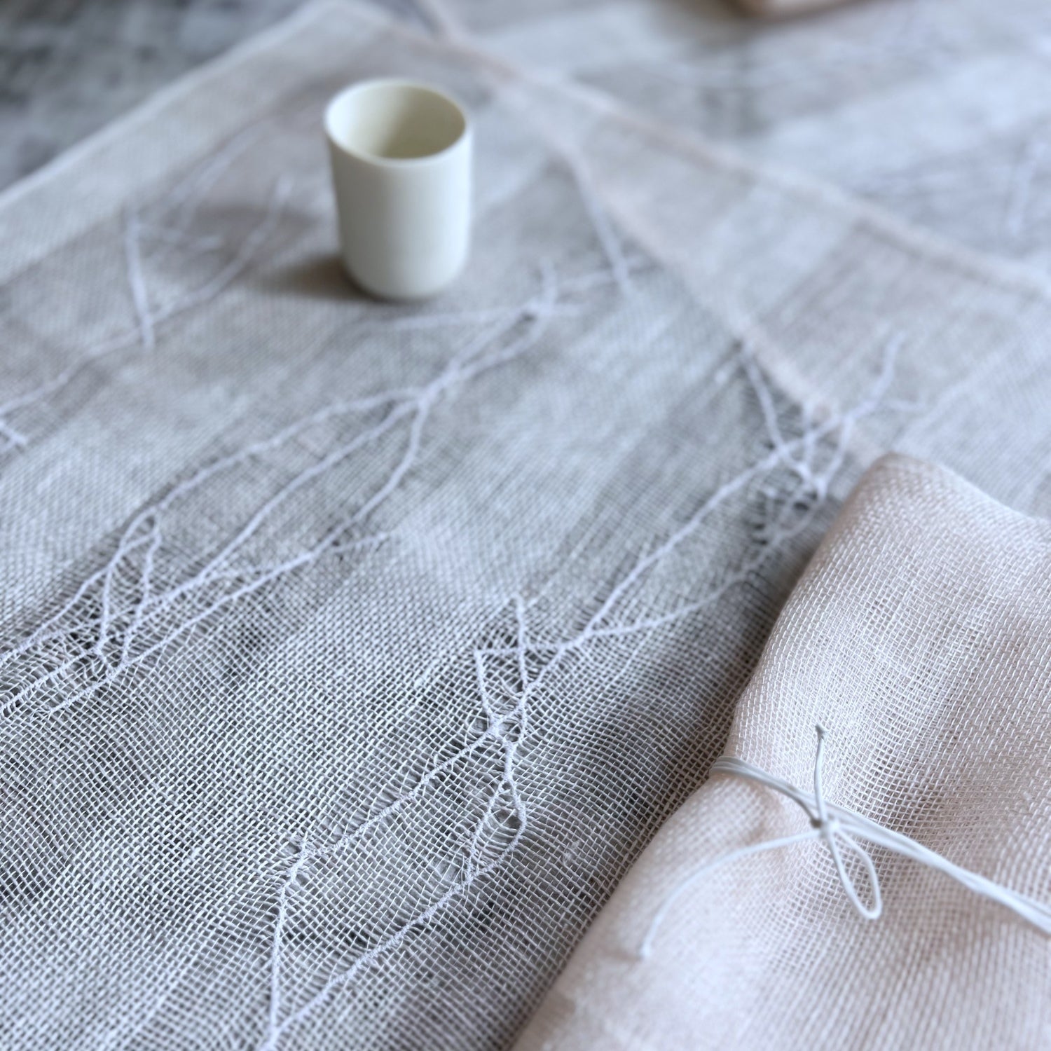 Handwoven linen napkin and placemat gift set in powder pink, that consists of 1 napkin 50x50 cm, 1 embroidered placemat 50x50 cm, and 1 silk napkin holder